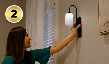 Woman sliding the Smart Sconce™ onto the mounting plate